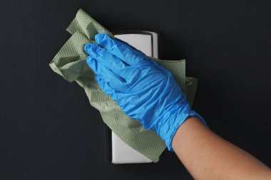 Kapalı mekanda kağıt havluyla eldiven temizleme düğmesi takan kadın.