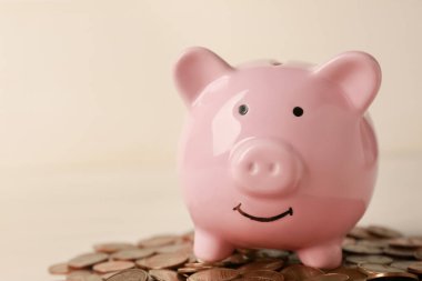 Seramik domuz kumbarası ve beyaz ahşap masaya madeni paralar, yakın plan. Metin için boşluk