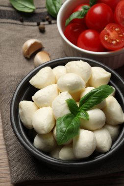 Nefis mozarella topları, domatesler ve fesleğen yaprakları masanın üstünde.