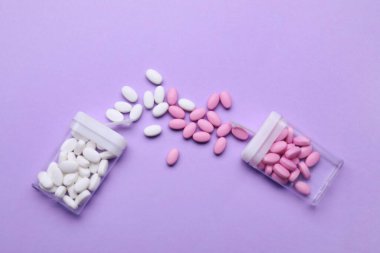 Konteynırlar ve eflatun arka planda farklı dragee şekerler, düz konum