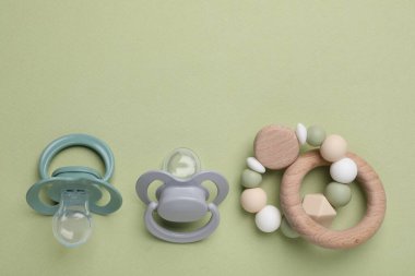 Düz kompozisyon, emzikler ve soluk yeşil arka planda diğer bebek eşyaları. Metin için boşluk