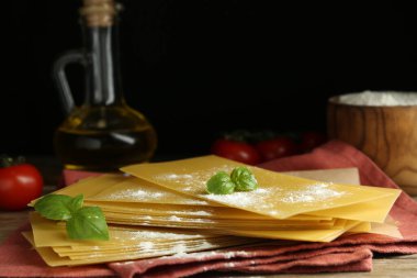 Ahşap masanın üzerinde pişmemiş lazanya çarşafları olan kompozisyon