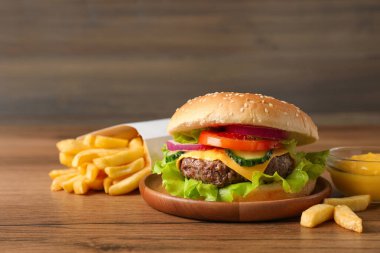 Tahta masada servis edilen lezzetli hamburger, sos ve patates kızartması.