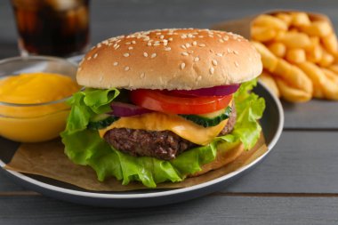 Lezzetli burger, gazoz ve patates kızartması. Gri ahşap masada servis ediliyor. Yakın plan.