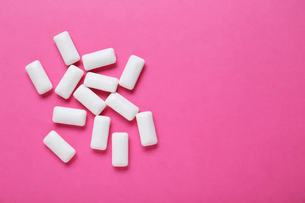 Tasty white chewing gums on pink background, flat lay. Space for text