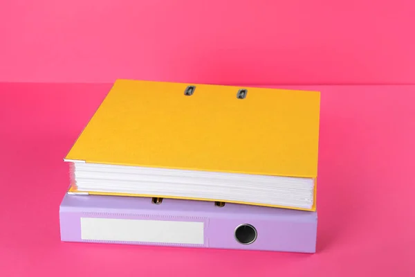 Bright hardcover office folders on pink background
