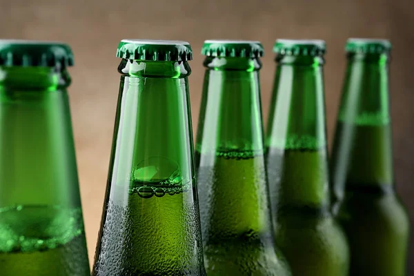 Many bottles of beer on light brown background, closeup