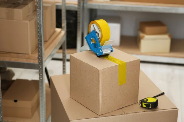 Taping cardboard box with adhesive tape dispenser indoors