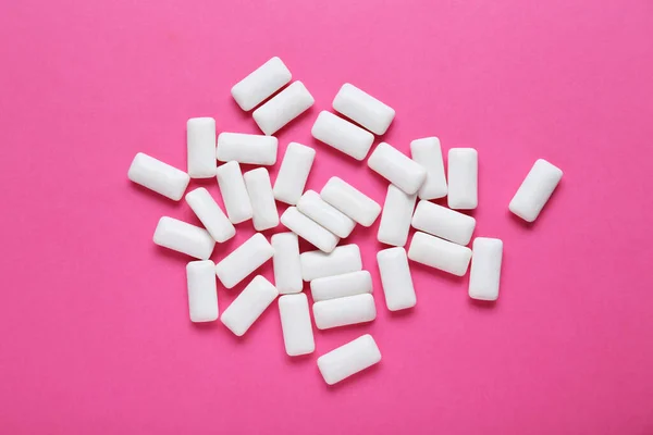 Tasty white chewing gums on pink background, flat lay