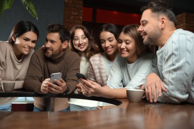 İçkili ve akıllı telefonlu arkadaşlar kafede birlikte vakit geçiriyorlar.