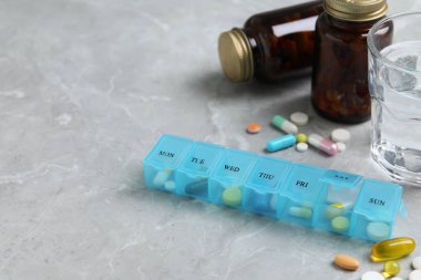 Gri mermer masa üzerinde ilaç bulunan haftalık ilaç kutusu. Metin için boşluk