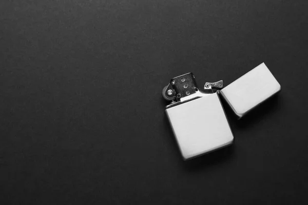 Gray metallic cigarette lighter on black background, top view. Space for text