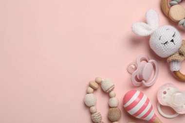 Düz kompozisyon, emzikler ve pembe arka planda diğer bebek eşyaları. Metin için boşluk