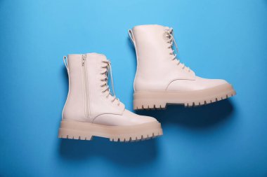 Açık mavi arka planda bir çift şık deri ayakkabı.