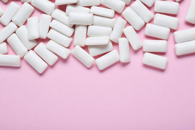 Soluk pembe arka planda leziz beyaz sakız çiğneme, düz yatış. Metin için boşluk