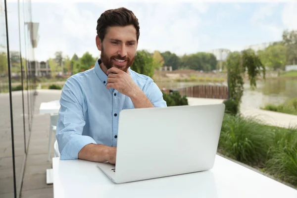 Handsome man with laptop in outdoor cafe