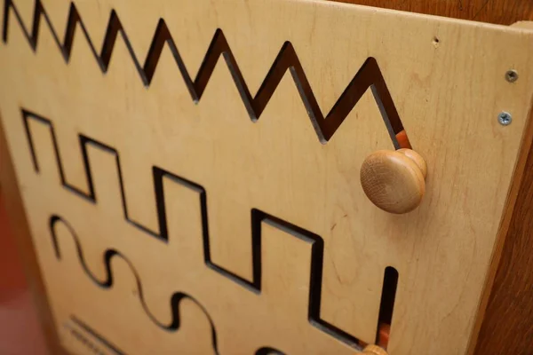 Wooden sliding maze with different lines on wall, closeup. Montessori toy