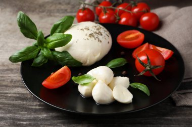 Domatesli ve fesleğenli lezzetli mozzarella ahşap masada, yakın plan.