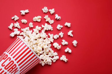 Kırmızı arka planda nefis patlamış mısırlı kağıt bardak, düz yatıyordu. Metin için boşluk