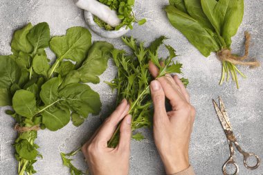 Açık gri masada taze yeşil otları olan bir kadın.