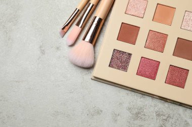 Göz farı paleti ve gri masadaki fırçalar düzdü. Metin için boşluk