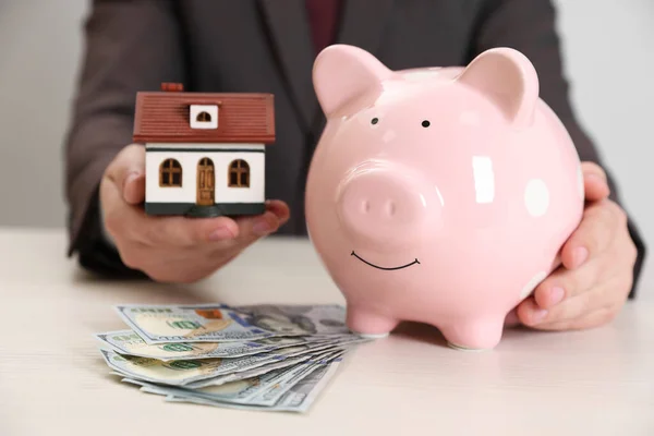 Man Holding House Model Piggy Bank Dollar Banknotes Wooden Table — Foto de Stock