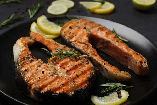 Stock image Plate with tasty salmon steaks on black table, closeup