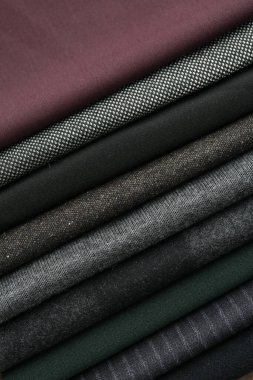 Arka plan olarak farklı kumaş örneklerinin yığını, yakın plan. Tekstil dokusu