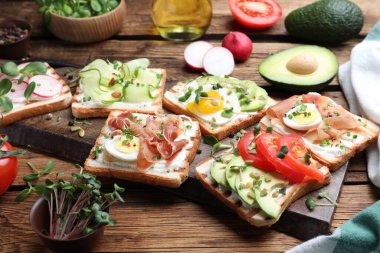 Farklı lezzetli sandviçler ve ahşap masada mikroyeşiller.