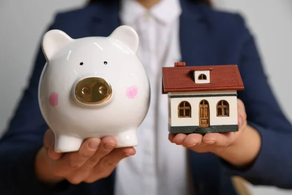 Woman Holding Piggy Bank Little House Model Light Grey Background — Foto de Stock
