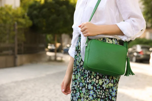 Woman with stylish green bag on city street, closeup. Space for text