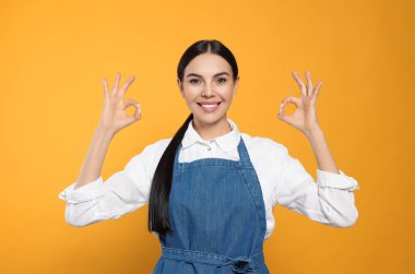 Sarı arka planda kot pantolonlu genç bir kadın.