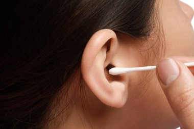 Kulağı pamuklu bezle temizleyen kadın, yakın plan.