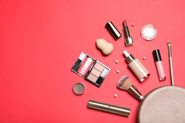 Kırmızı arka planda kozmetik poşeti olan farklı makyaj ürünleri. Metin için boşluk