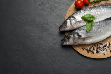 Deniz levreği ve malzemeler siyah masada, üst manzara. Metin için boşluk