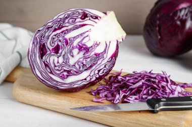 Beyaz ahşap masada bıçakla taze kırmızı lahana kes, yakın plan.