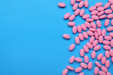 Mavi arka planda bir sürü pembe dragee şekeri var. Metin için boşluk