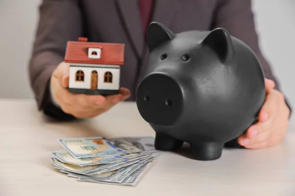 Man Holding House Model Piggy Bank Dollar Banknotes Wooden Table — Foto de Stock