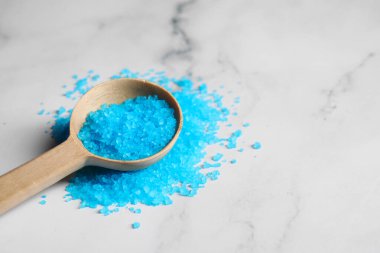 Tahta kaşık, beyaz mermer masada açık mavi deniz tuzu. Metin için boşluk