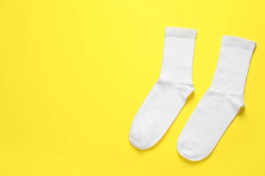 Sarı arka planda bir çift beyaz çorap, düz yatış. Metin için boşluk