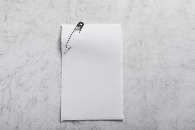 Gri desenli arka plan üzerine çengelli iğne iliştirilmiş kağıt yaprak, üst görünüm