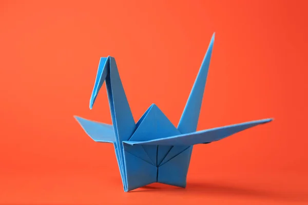 Origami art. Handmade paper crane on orange background, closeup