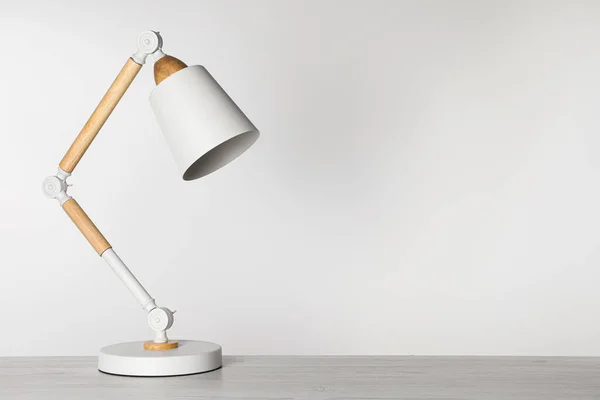 Stylish modern desk lamp on white wooden table, space for text