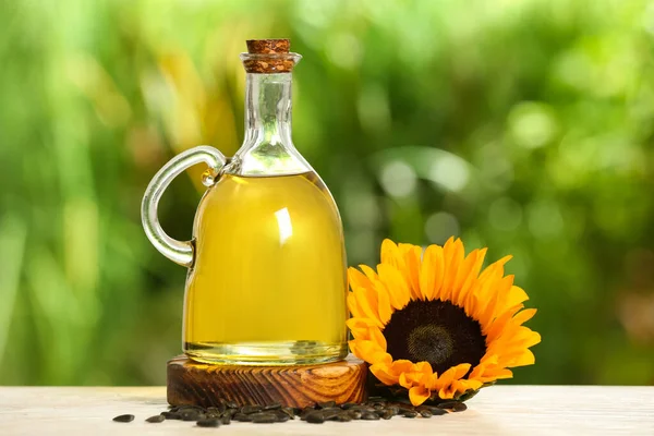 Sunflower cooking oil, seeds and yellow flower on white wooden table outdoors