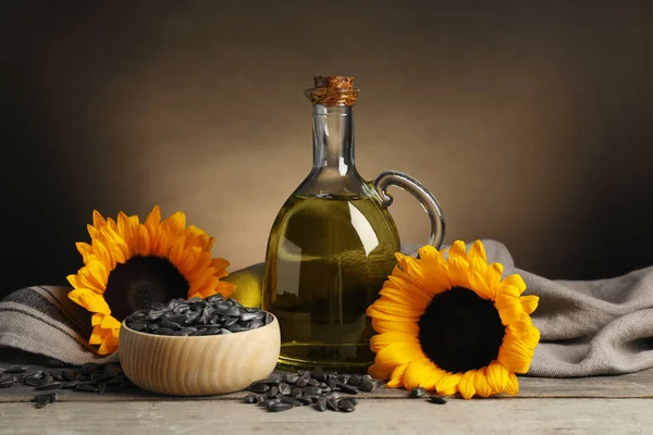 Sunflower cooking oil, seeds and yellow flowers on light grey table
