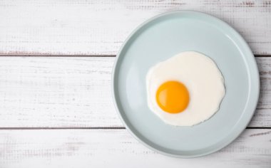 Beyaz ahşap masada tabakta leziz kızarmış yumurta, üst manzara. Metin için boşluk