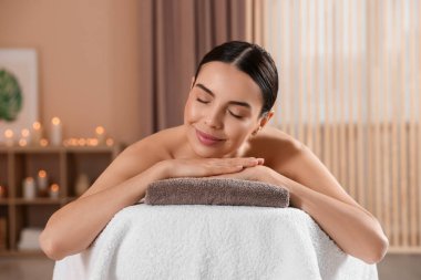 Genç bir kadın masaj salonundaki masaj koltuğunda dinleniyor.