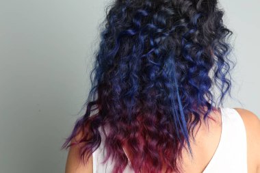 Gri arka planda parlak boyalı saçları olan genç bir kadın.