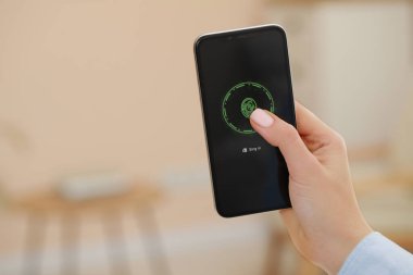 İçeride parmak izi tarayıcısıyla akıllı telefonun kilidini açan kadın, yakın plan. Metin için boşluk