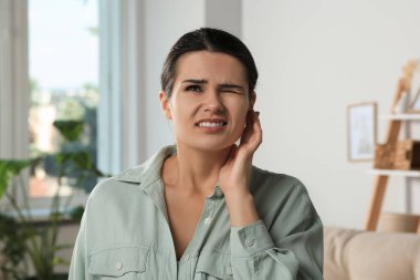 Evde kulak ağrısı çeken genç bir kadın.